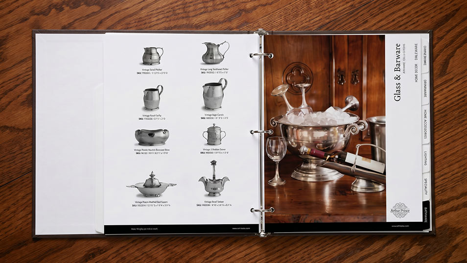 Photo of Arte Italica Glass and Barware section of print catalog on oak table