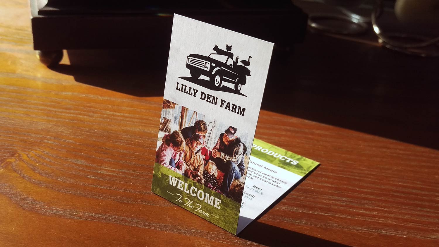 Photo of Lilly Den Farm business cards on a wood table